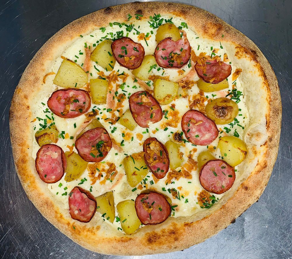 Pizza à la crème, saucisse, pommes de terre dorées et ciboulette.