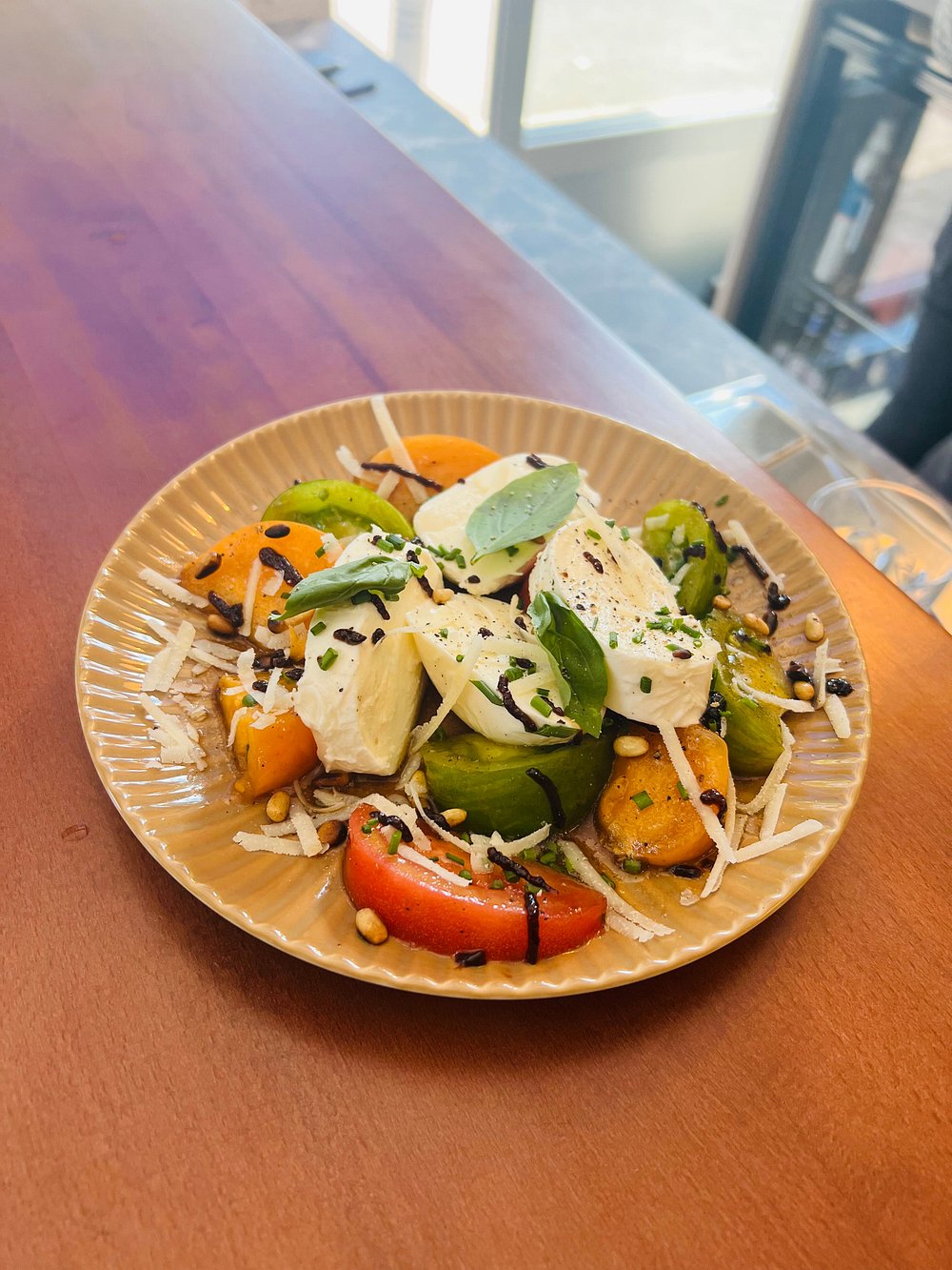 Assiette de mozzarella fraîche, poivrons grillés et noisettes concassées.